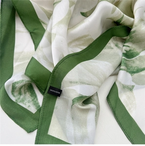 Detail of green floral silk scarf showing 100% polyester fabric texture and care label