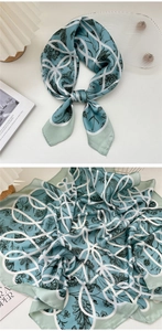 Detail of silk-like neckerchief with teal floral pattern and white geometric patterns