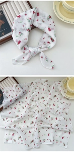 Macro detail of white linen scarf featuring delicate red cherry patterns and soft texture