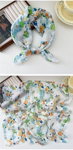 Detailed close-up of a white linen scarf with colorful floral patterns and fine stitching