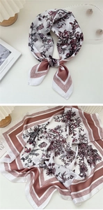 Detail of floral silk scarf with butterfly patterns and pink border laid on a white desk
