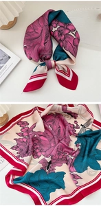 Detail of floral and dragonfly print silk scarf with striped border on a white table