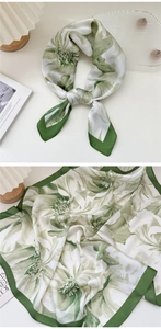 Detail of floral print silk scarf in green and white with elegant satin texture