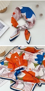 Detail of floral silk square scarf with bold orange and navy blue flower pattern