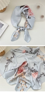Detailed view of floral silk scarf featuring pink peony patterns and blue-grey satin fabric