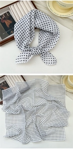 Detailed macro view of white cotton linen scarf with black polka dots on white desk