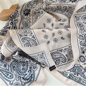 Dettaglio di un foulard quadrato in poliestere color crema con motivo paisley e fiori