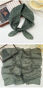 Close-up of soft dark green polka dot linen scarf tied in a bow on a white surface