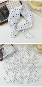 Detail of a lightweight black polka dot chiffon scarf styled with elegant accessories