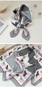 Dettaglio di un foulard in seta grigio e rosso con motivo equestre e bordo a righe