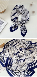 Dettaglio della sciarpa in seta con stampe blu di corone e catene con finitura satinata