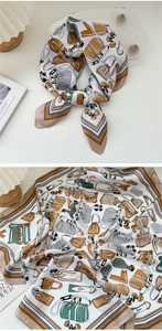 Dettaglio ravvicinato di un foulard in seta bianca con motivi di borse vintage e bordi