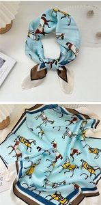 Dettaglio di un foulard in seta celeste con stampe equestri e bordi geometrici a contrasto