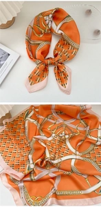 Dettaglio di un foulard in seta arancione con stampa a catena vintage e raso lucido