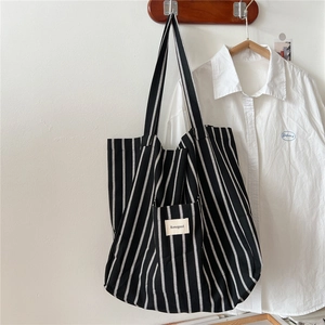 Minimalist black and white striped canvas tote bag with a small front pocket and logo