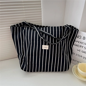 Close-up of black and white striped canvas tote bag with brand label on a white table