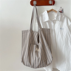 Detailed texture of striped canvas tote bag with front pocket hung on a wooden hook