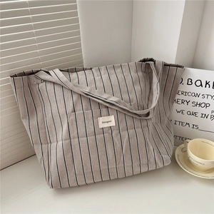 Detailed view of the striped canvas tote bag with woven logo and durable wide handles