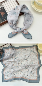 Macro detail of a light grey floral silk scarf showing delicate patterns and hem colors
