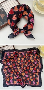 Close-up of black square scarf featuring colorful heart prints and delicate red border