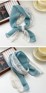 Detailed close-up of blue linen scarf with white lace embroidery and delicate floral pattern