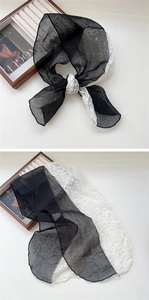 Detailed close-up of long black chiffon scarf with delicate white floral lace embroidery
