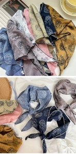 Detail of paisley print triangle scarf with white scalloped crochet edge and pastel colors