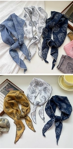 Close-up of paisley triangle scarves with elegant embroidered wavy edges and soft texture