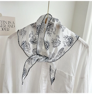 Detail of paisley print neckerchief with black wavy edge on a white silk scarf