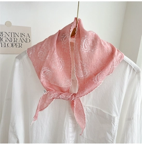Close-up of pink paisley silk scarf with lace trim tied on a white cotton shirt