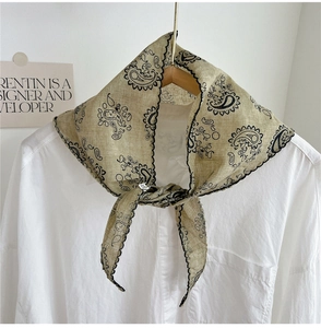 Detailed view of paisley silk scarf tied on a white shirt collar with scalloped edges