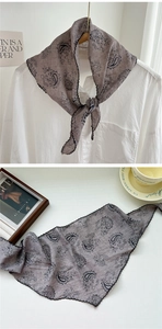 Close-up of grey paisley triangular scarf with black embroidered wavy edges and soft texture
