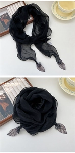 Détail d'une écharpe en mousseline noire plissée avec feuilles brodées et pompons
