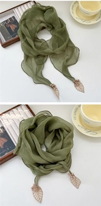 Gros plan sur une écharpe plissée vert foncé avec broderie de feuilles et pompons doux