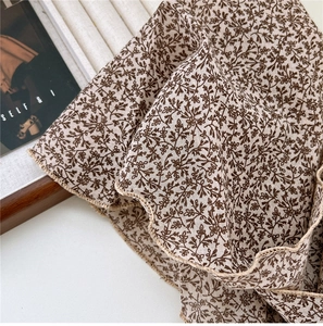 Macro detail of floral linen scarf showing ruffle edges and premium fabric texture