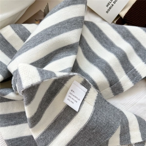 Nahaufnahme des gestreiften Strickschals mit Materialetikett aus Acryl und Nylon