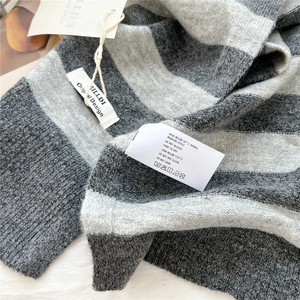 Detail of striped knitted shawl showing fabric texture and care label with brand tag