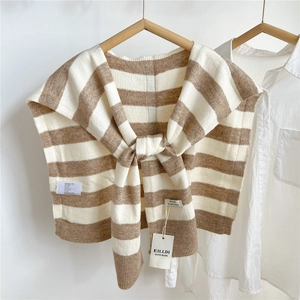 Detail of striped knitted shawl with brand tags hung on a wooden hanger with white shirt