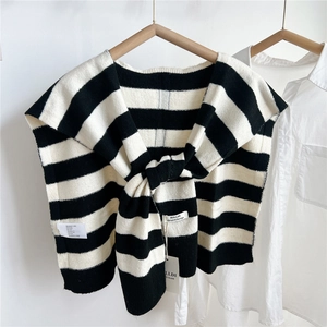 Detail of striped knit shawl with brand label and care tag over a white shirt