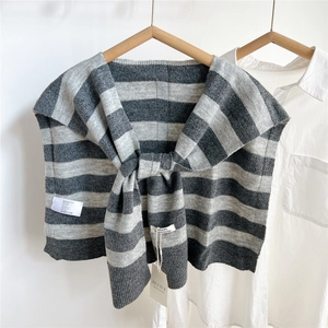 Detail of grey striped knit shawl over a white shirt showing texture and ribbing