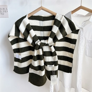 Close-up of striped knitted shawl with brand label layered over a white shirt