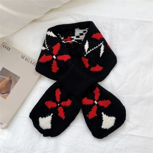 Detailed knit texture of a black scarf with bold red and white geometric star patterns
