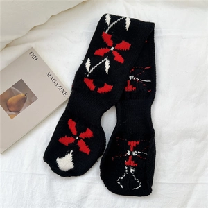 Close-up of black knit scarf with red floral jacquard pattern and thick texture
