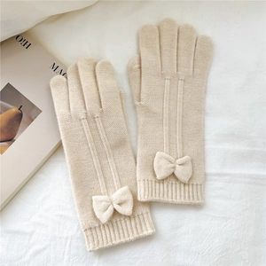Detailed texture of beige knitted gloves with a 3D bow design on soft linen fabric