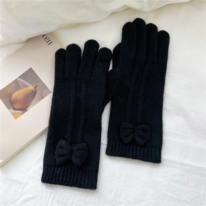 Detail of black knit touchscreen gloves with cute bow decoration on white fabric