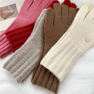 Close-up of knit gloves in pink, red, grey and beige with ribbed cuffs and metal logo