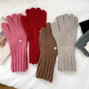 Detail of knit gloves with ribbed cuffs and decorative golden metal buttons in multi-colors