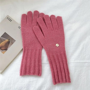 Close-up of pink knit gloves with long ribbed cuffs and elegant gold logo detail