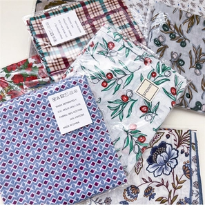 Detail of assorted printed cotton scarves showing fabric texture and material labels