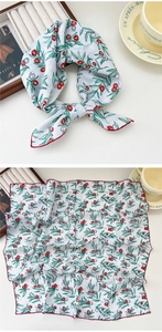 Detail of floral silk scarf with green leaves and red berries on a light blue background